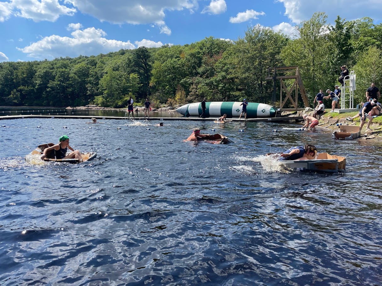 SONA Events team paddling across the lake in their homemade cardboard boats